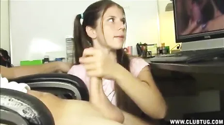 A namorada dele dá uma punheta nele enquanto ele assiste a um vídeo pornô