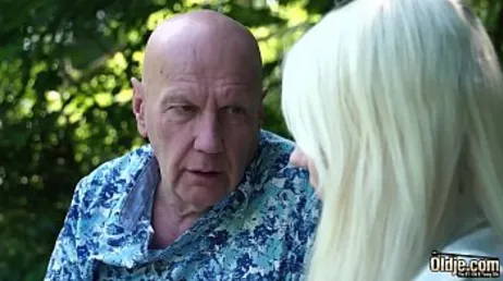 De grootvader legt zijn handen op zijn kleindochter van in de twintig, een heerlijke blondine.