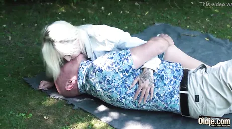 De grootvader legt zijn handen op zijn kleindochter van in de twintig, een heerlijke blondine.