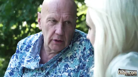 De grootvader legt zijn handen op zijn kleindochter van in de twintig, een heerlijke blondine.