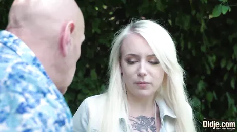 De grootvader legt zijn handen op zijn kleindochter van in de twintig, een heerlijke blondine.